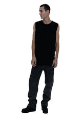 Man wearing a black sleeveless shirt and dark pants on a white background