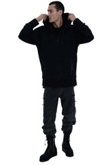 Person wearing a black hoodie, gray pants, and black boots on a white background