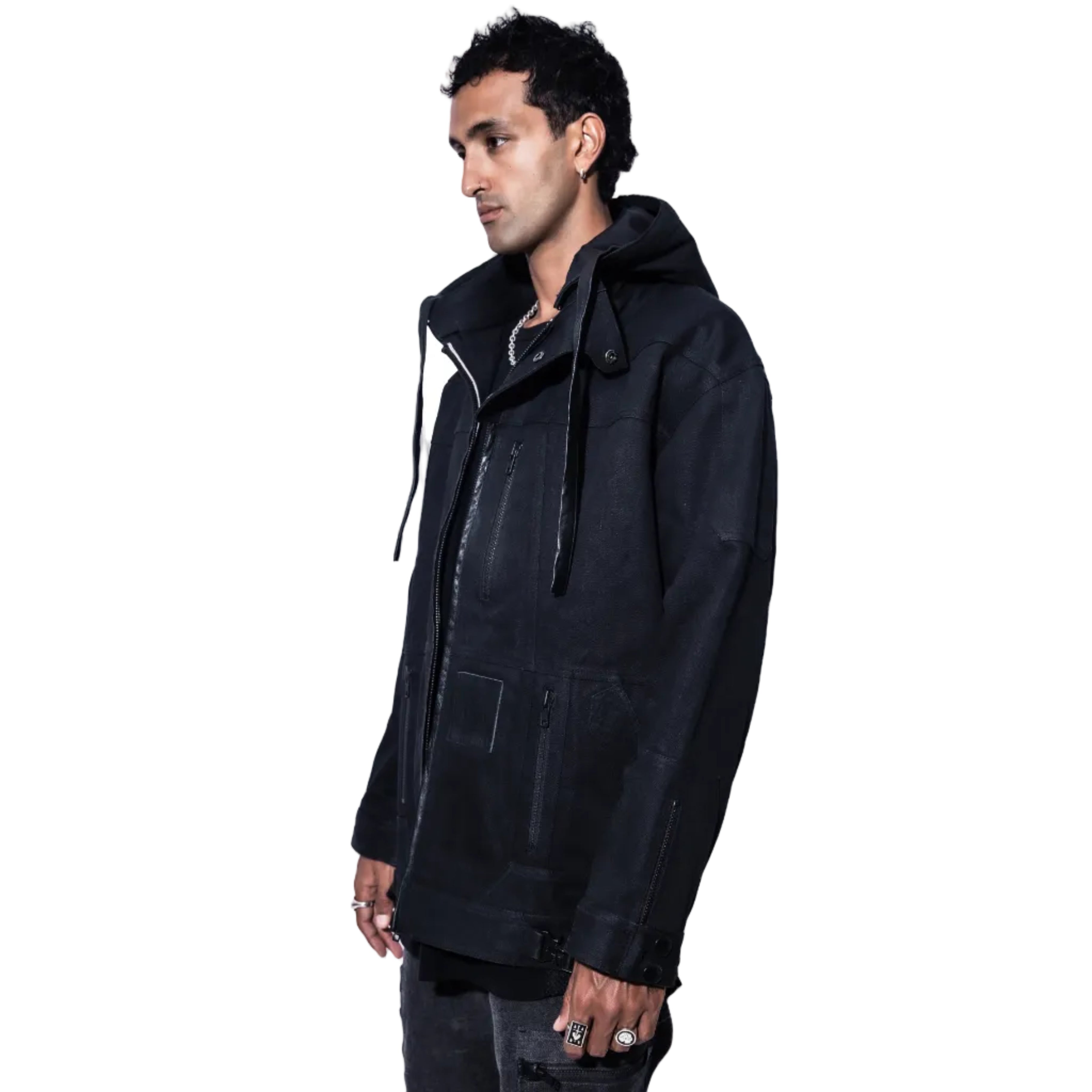 A man wearing a black hooded jacket with multiple zippered pockets, shown in profile against a solid white background.